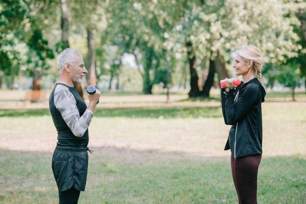 Iäkäs mies ja nainen treenaamassa punteilla puistossa.