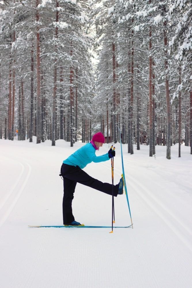 Nainen suksilla. Etummainen jalka on ojennettu eteen niin, että etummaisen jalan suksi on pystyssä maassa. 