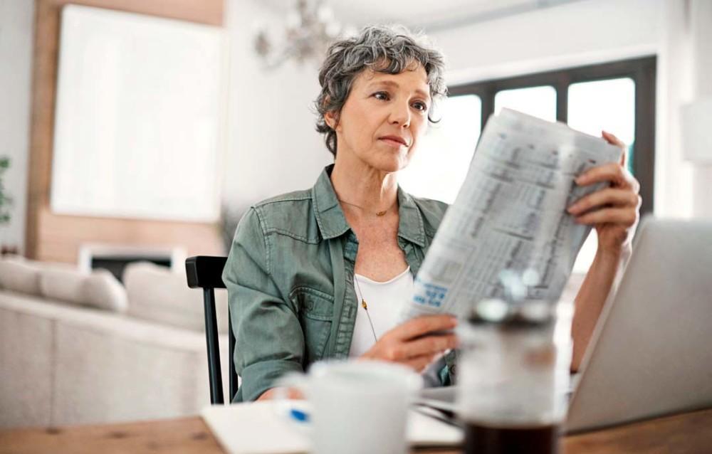 nainen lukee sanomalehteä
