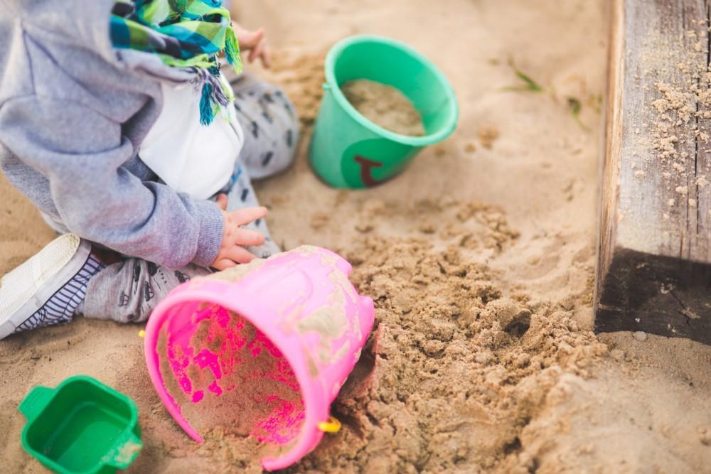 Lapsi leikkii hiekkalaatikossa ämpäreillä