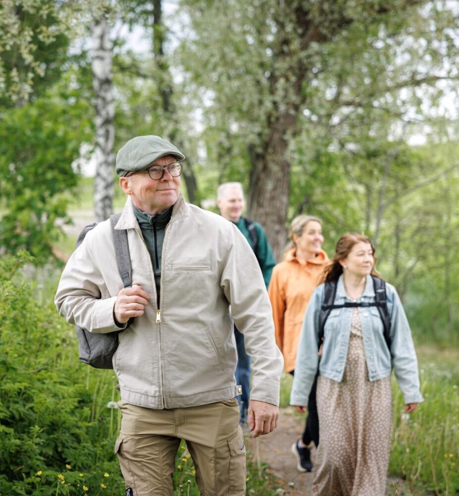 Kuvituskuva. Kaksi miestä ja naista kävelee metsäisellä polulla.