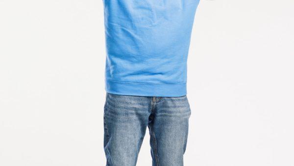 Mies sinisessä paidassa hymyilee kädet ylhäällä voittaja